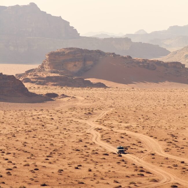 Truck driving in desert with mountains.