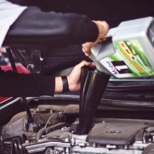 Man pouring oil into car engine.