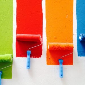 Paint rollers painting different colors on a white wall.