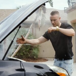 Man standing in front of smoking car.