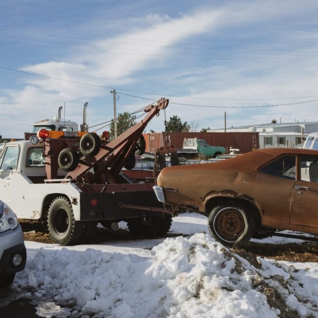 Truck towing rusty car.