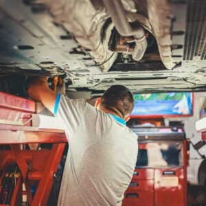 Man working under a car on a lift.